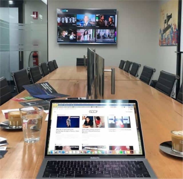 Close up of laptop in board room with large screen in background